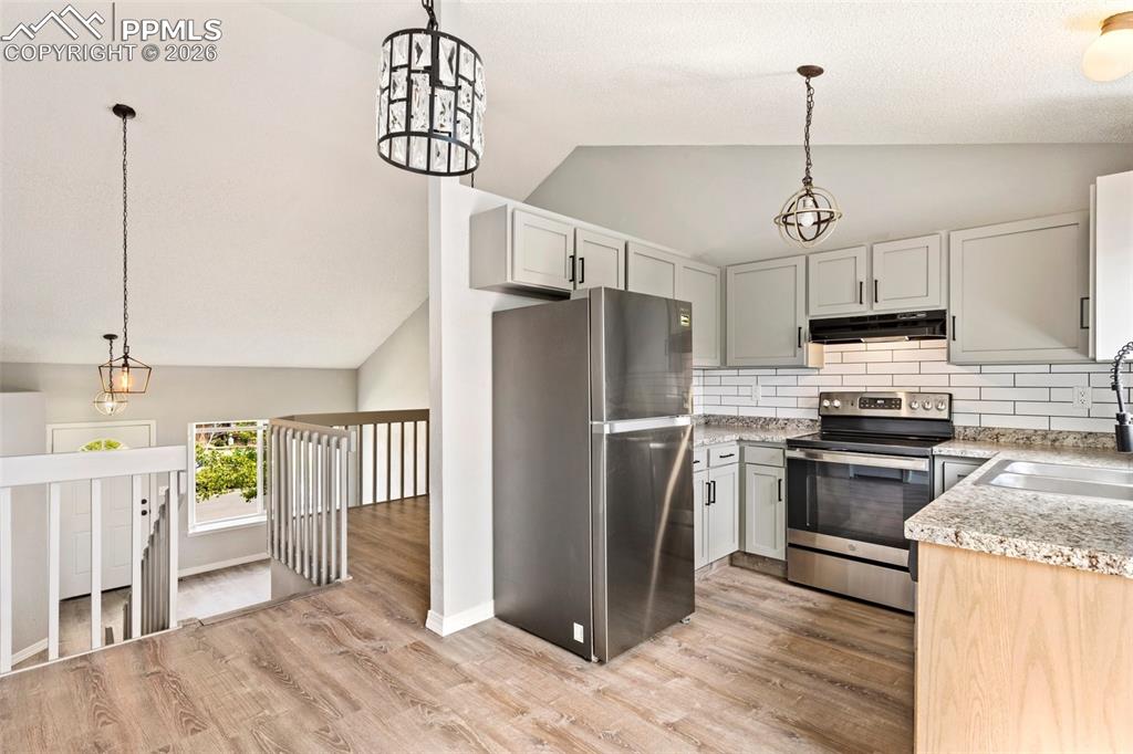 Image 13 of 35: Kitchen featuring stainless steel appliances, light stone counters, hanging