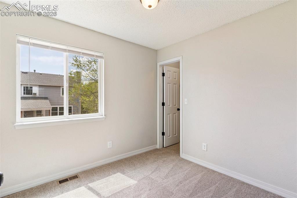 Image 15 of 35: bedroom featuring light colored carpet and a textured ceiling