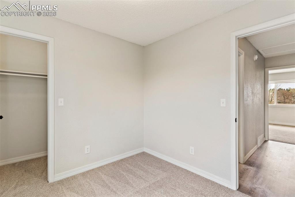 Image 16 of 35: Unfurnished bedroom featuring light carpet, a spacious closet, and a textur