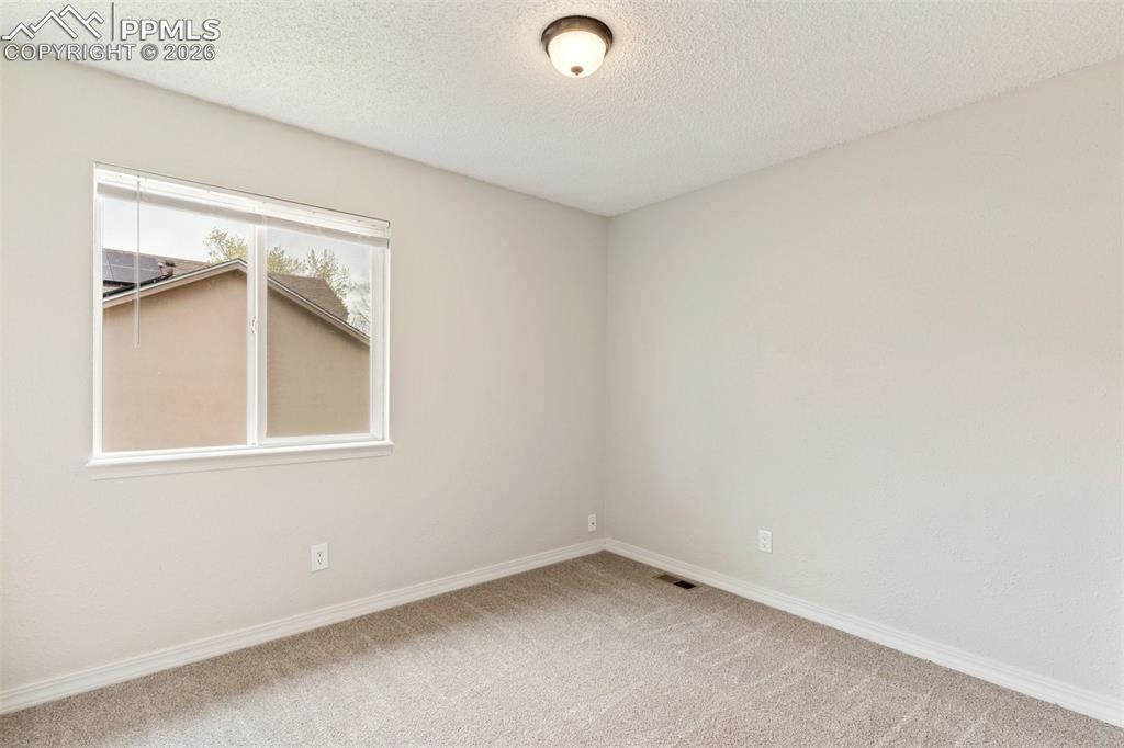 Image 18 of 35: Bedroom featuring light carpet and a textured ceiling