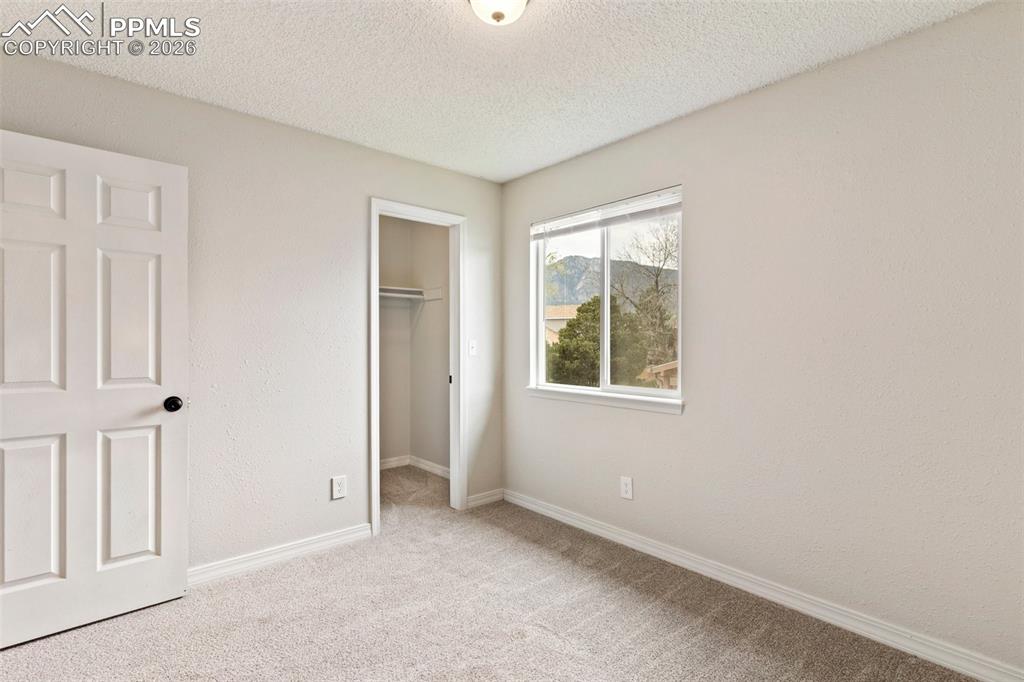 Image 19 of 35: Unfurnished bedroom featuring a walk in closet, a textured ceiling, light c