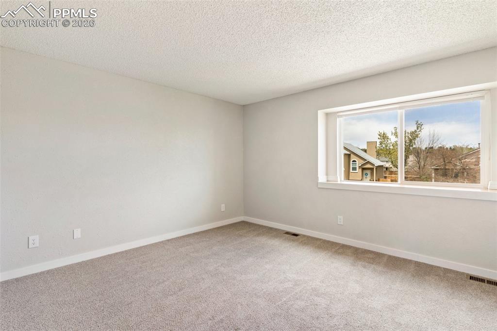 Image 21 of 35: Bedroom with light colored carpet and a textured ceiling