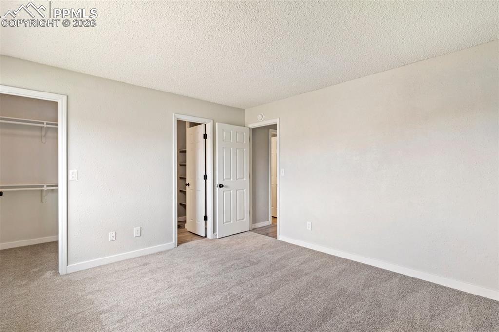 Image 22 of 35: Master Bedroom with a walk in closet, a textured ceiling, light colored car
