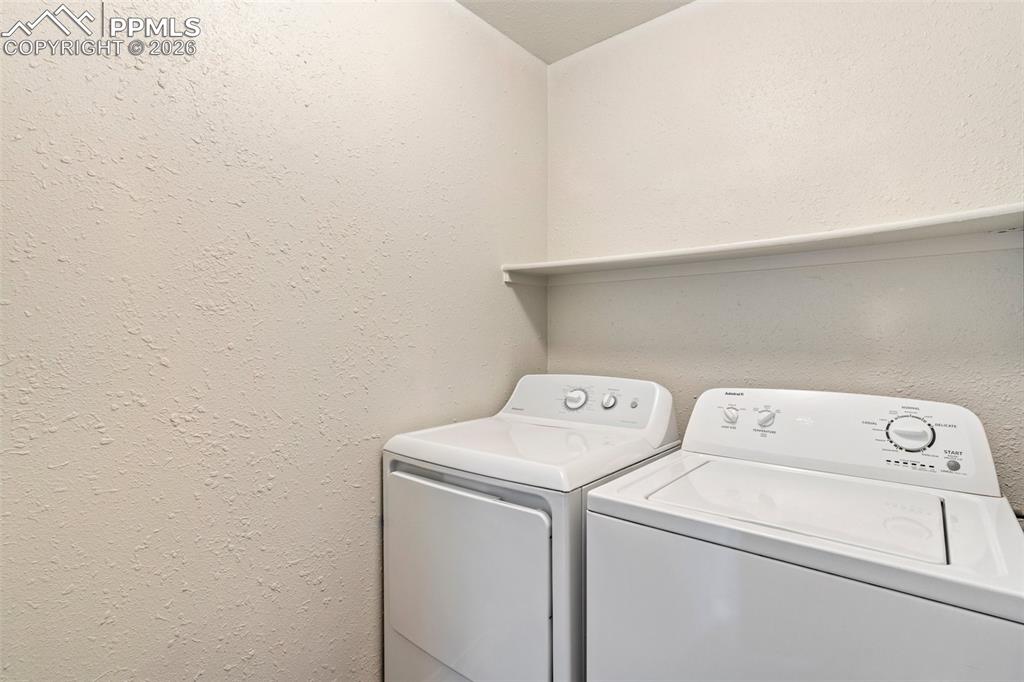 Image 23 of 35: Laundry room with lofted ceiling, washer and dryer, and a textured wall
