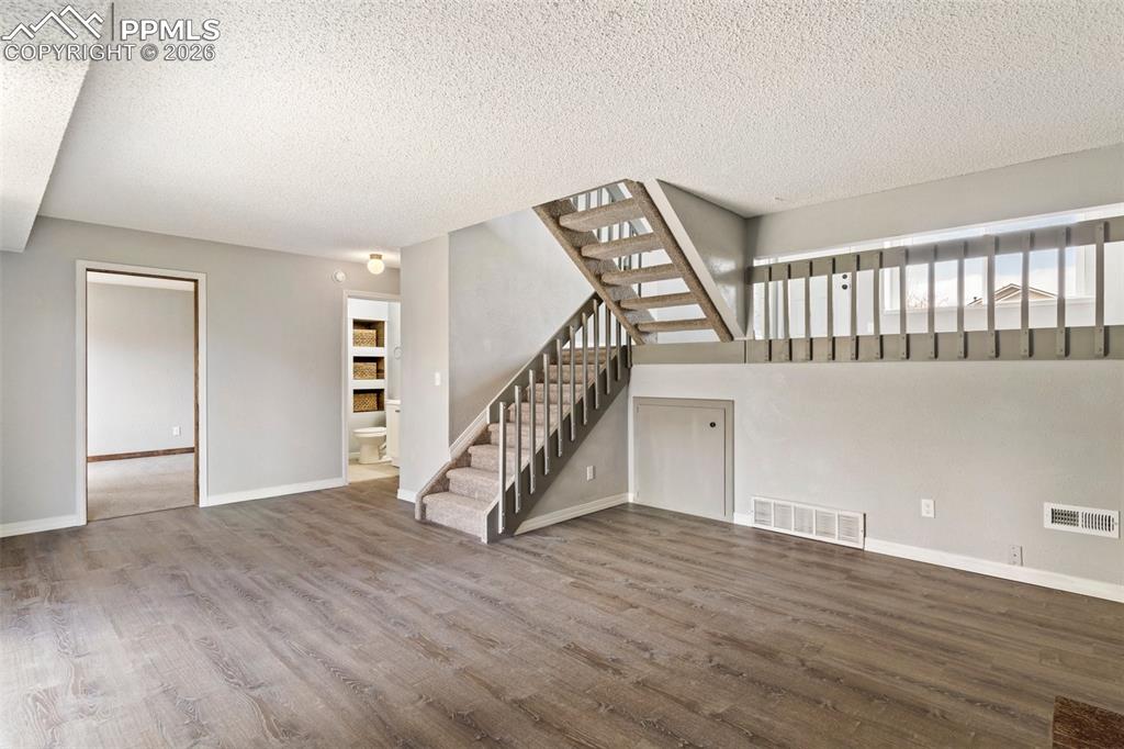 Image 24 of 35: 
family room in walkout basement with wood finished floors and a textured c