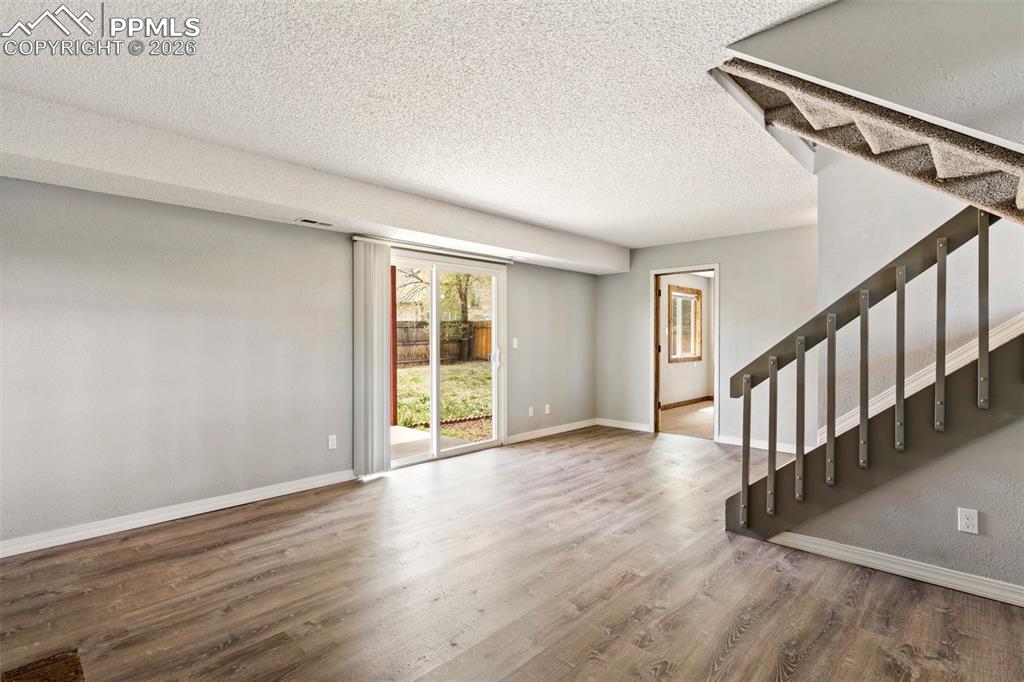 Image 25 of 35: family room in walkout basement with wood finished floors and a textured ce