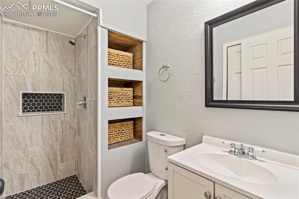 Image 27 of 35: 3/4 basement bathroom featuring a textured wall, a stall shower, and vanity