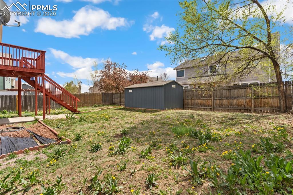 Image 30 of 35: Fenced backyard with a wooden deck and a shed