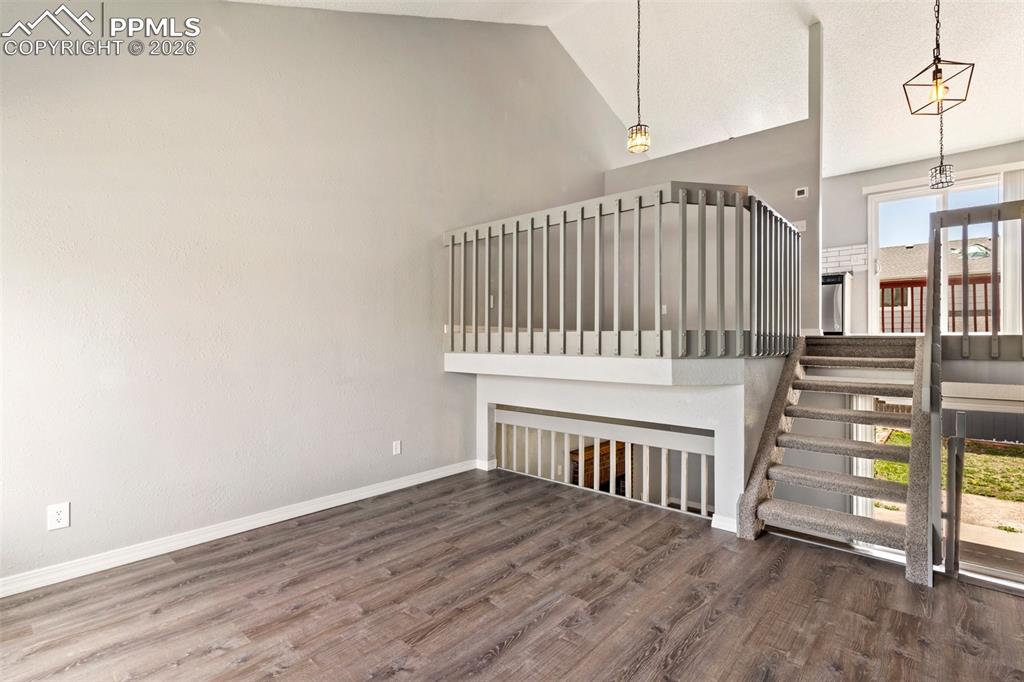 Image 6 of 35: Stairway with wood finished floors and a high ceiling