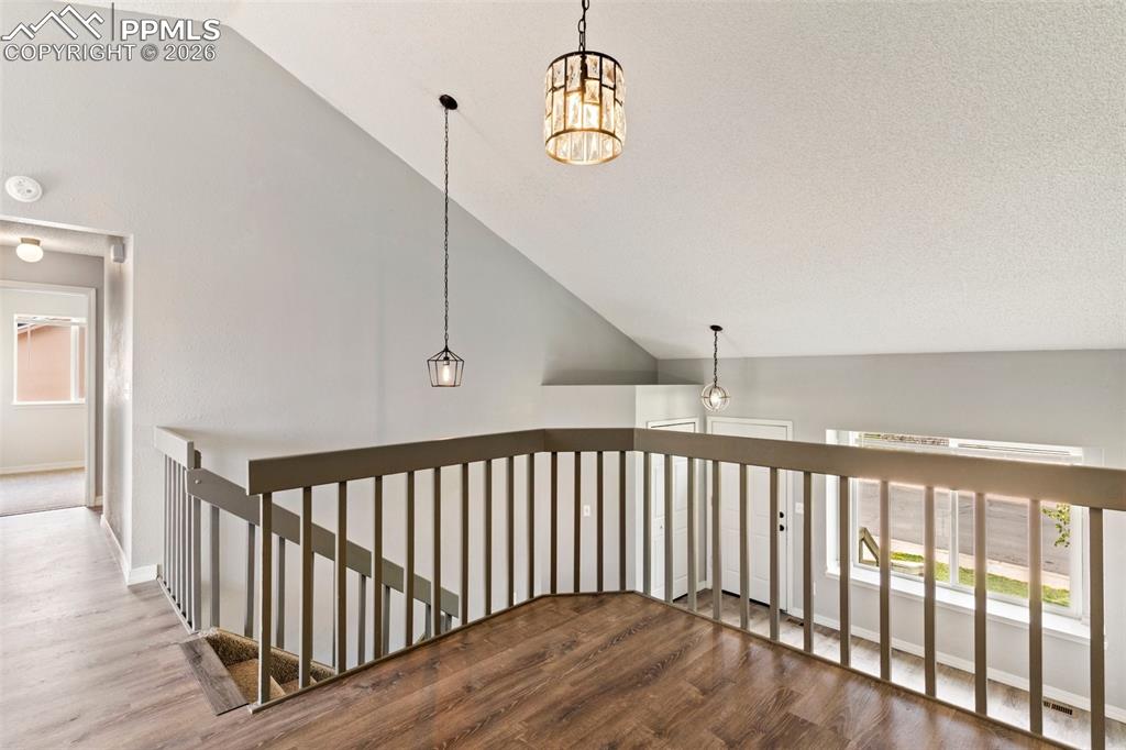 Image 9 of 35: Hall with wood finished floors, lofted ceiling, an upstairs landing, and su