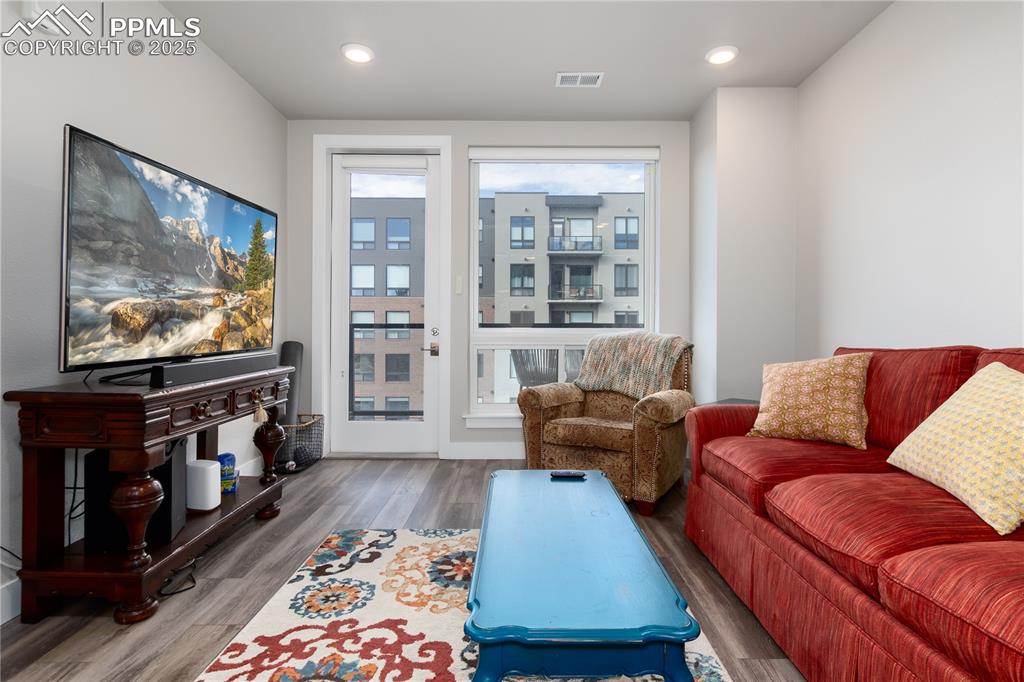 Image 10 of 21: Living room with wood finished floors and recessed lighting