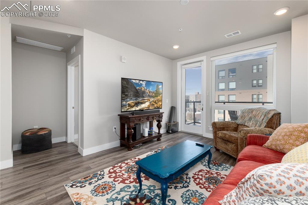 Image 11 of 21: Living room with wood finished floors and recessed lighting