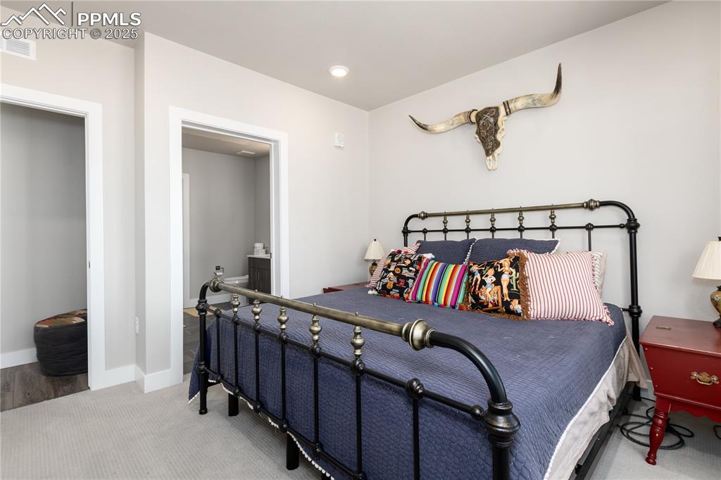 Image 16 of 21: Carpeted bedroom with ensuite bath and recessed lighting