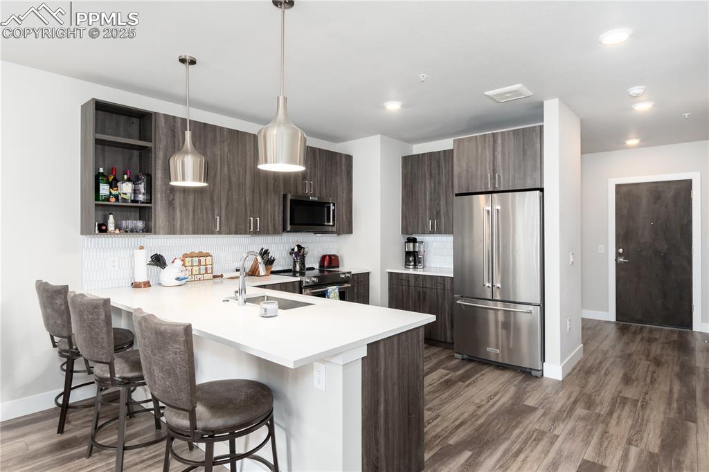 Image 3 of 21: Kitchen featuring stainless steel appliances, light countertops, dark wood-