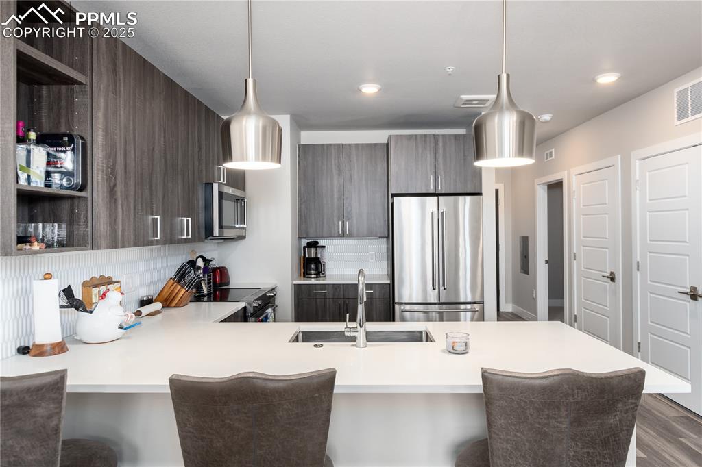 Image 6 of 21: Kitchen featuring modern cabinets, appliances with stainless steel finishes