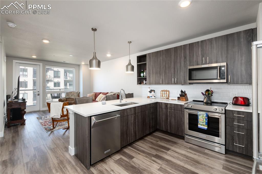 Image 7 of 21: Kitchen with stainless steel appliances, dark brown cabinets, open shelves,