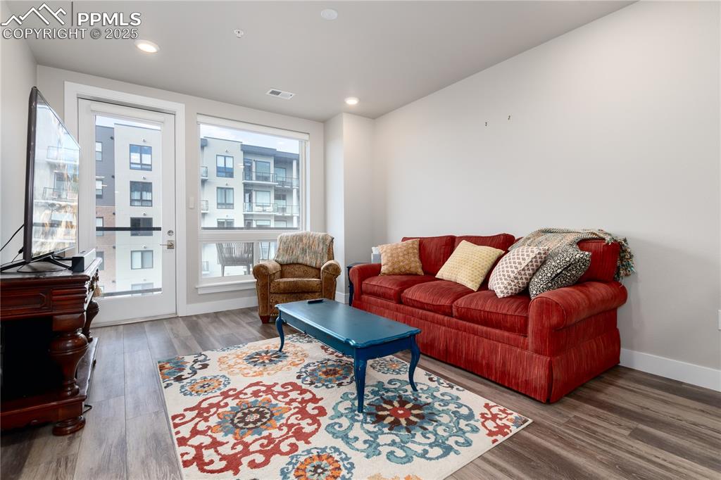 Image 9 of 21: Living room with wood finished floors and recessed lighting