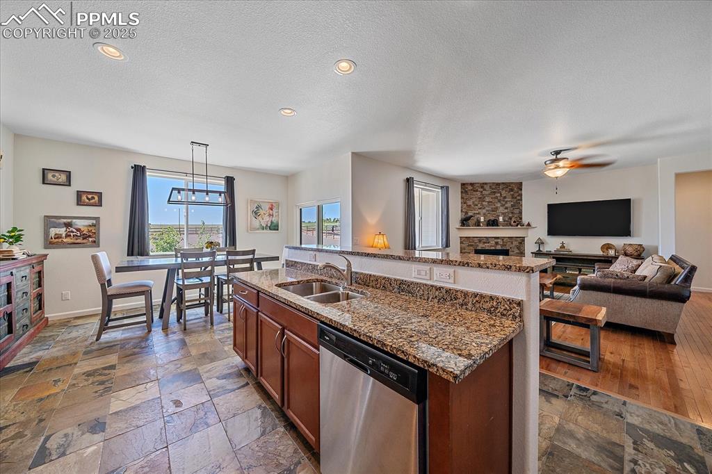 Image 12 of 35: Kitchen with dishwasher, a sink, stone tile flooring, a ceiling fan, and a 