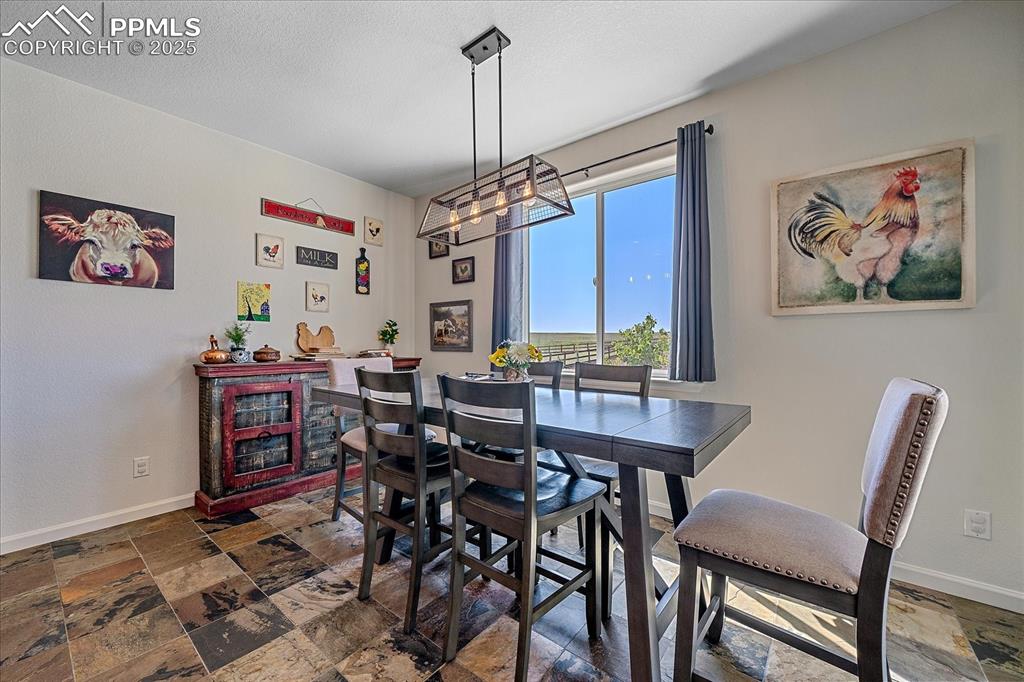 Image 13 of 35: Dining space featuring stone tile floors, a chandelier, and baseboards
