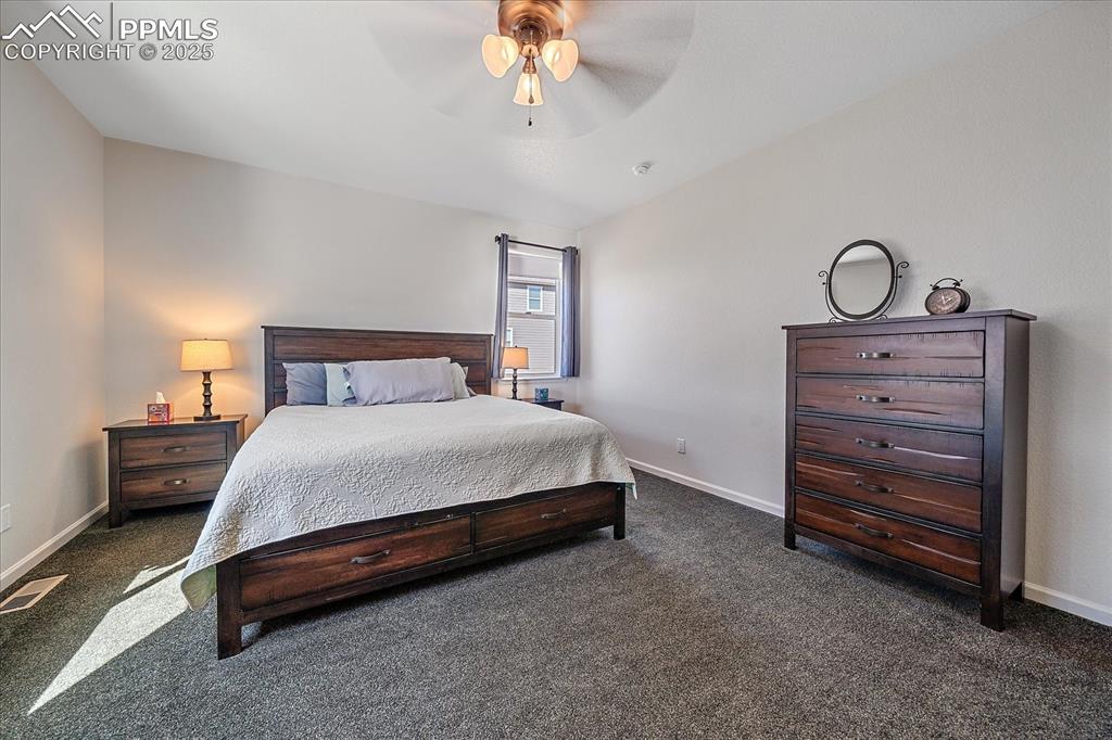 Image 15 of 35: Bedroom featuring dark carpet, baseboards, and a ceiling fan