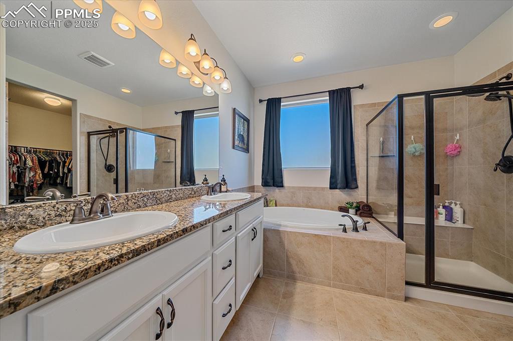 Image 16 of 35: Bathroom with a stall shower, a garden tub, a spacious closet, tile pattern