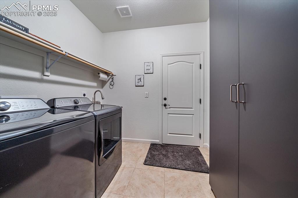 Image 22 of 35: Washroom with washer and dryer, light tile patterned floors, and baseboards