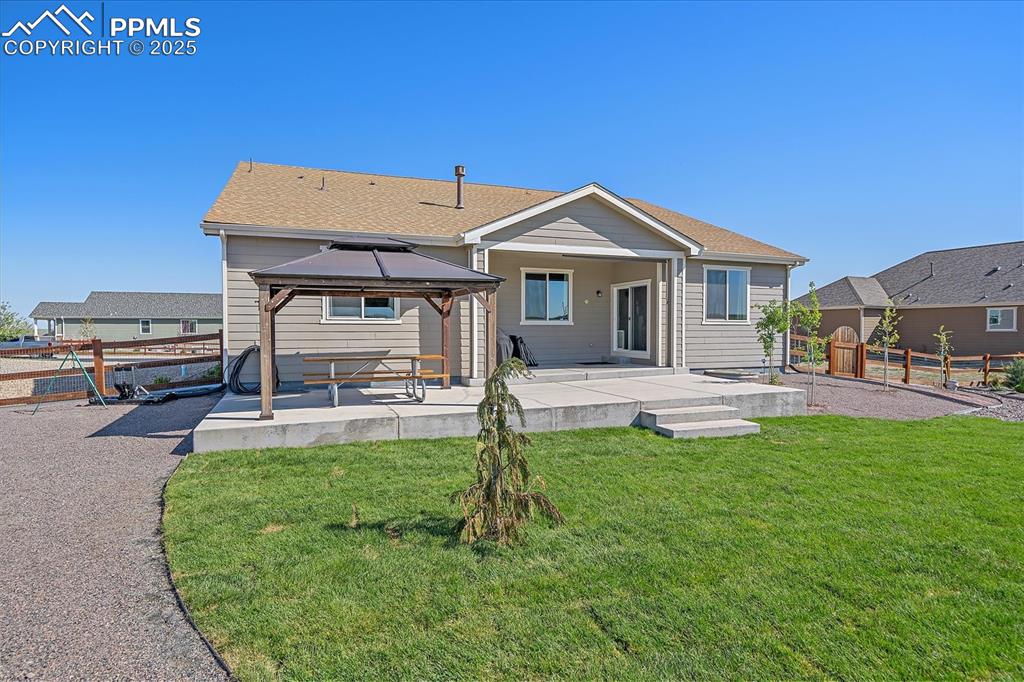 Image 24 of 35: Rear view of house featuring a gazebo, a patio area, and roof with shingles