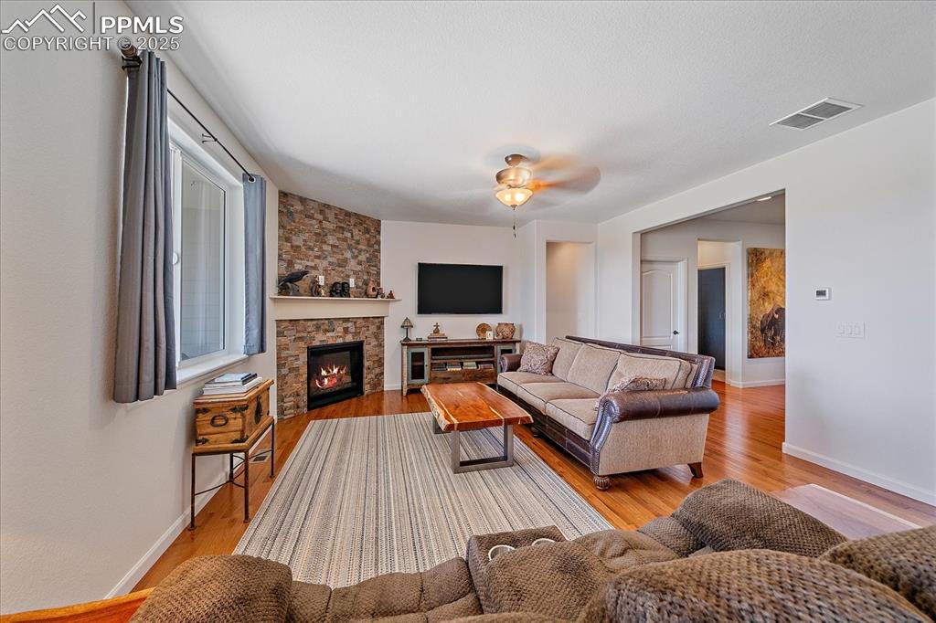 Image 8 of 35: Living room featuring wood finished floors, baseboards, a stone fireplace, 