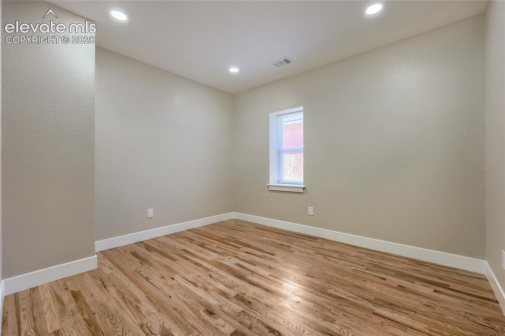 Image 32 of 49: A generous-sized third bedroom features soft natural light, hardwood floori