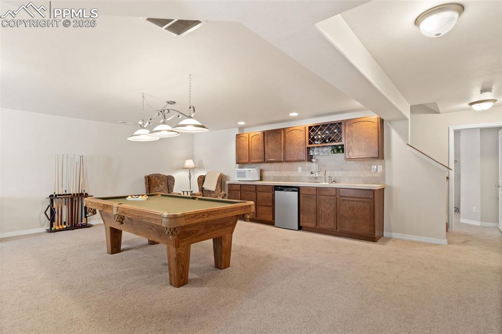 Image 21 of 31: Spacious family room with wet bar, fireplace & included pool table