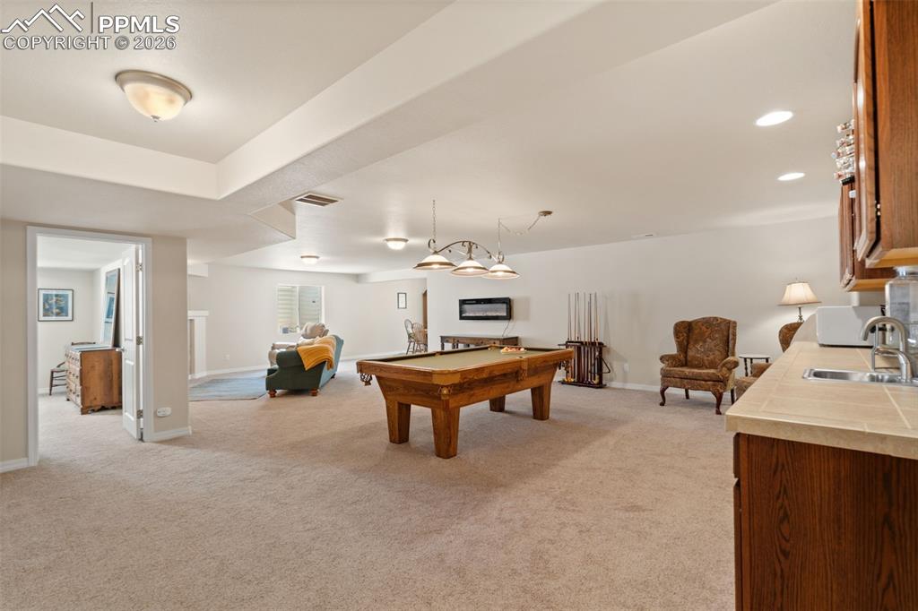 Image 22 of 31: Spacious family room with wet bar, fireplace & included pool table