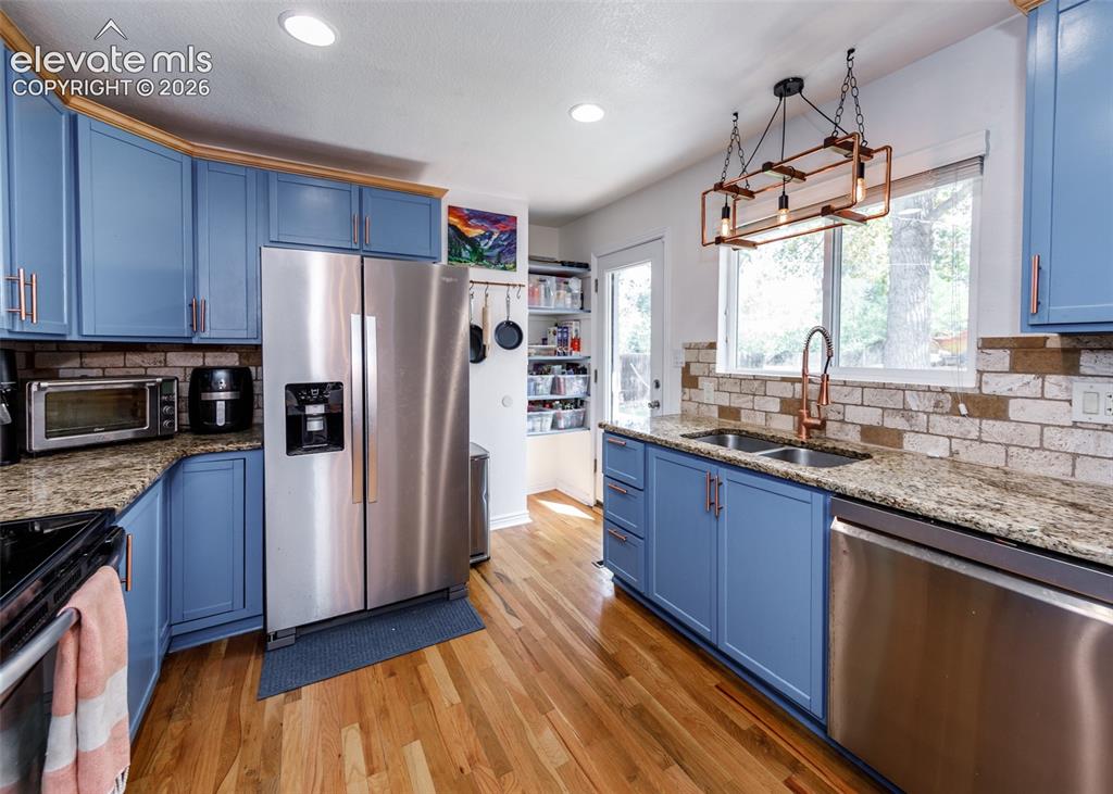 Image 13 of 47: Hardwood flooring, light blue cabinetry with rose gold hardware, granite co