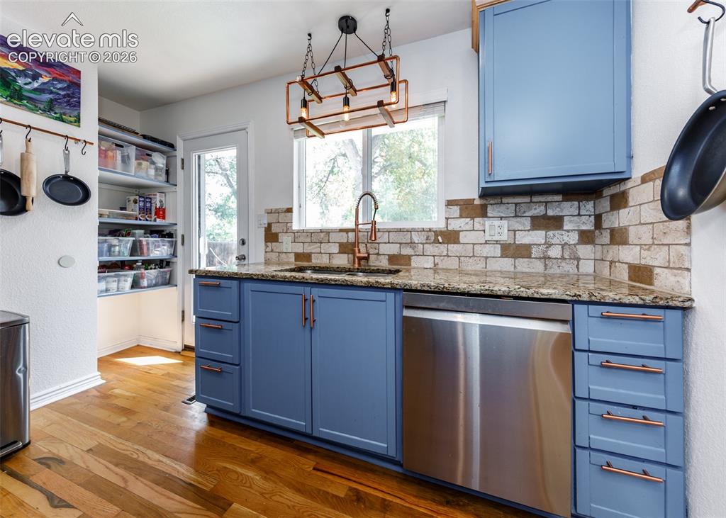 Image 14 of 47: Kitchen featuring wood-finish flooring, blue cabinetry with copper-toned ha
