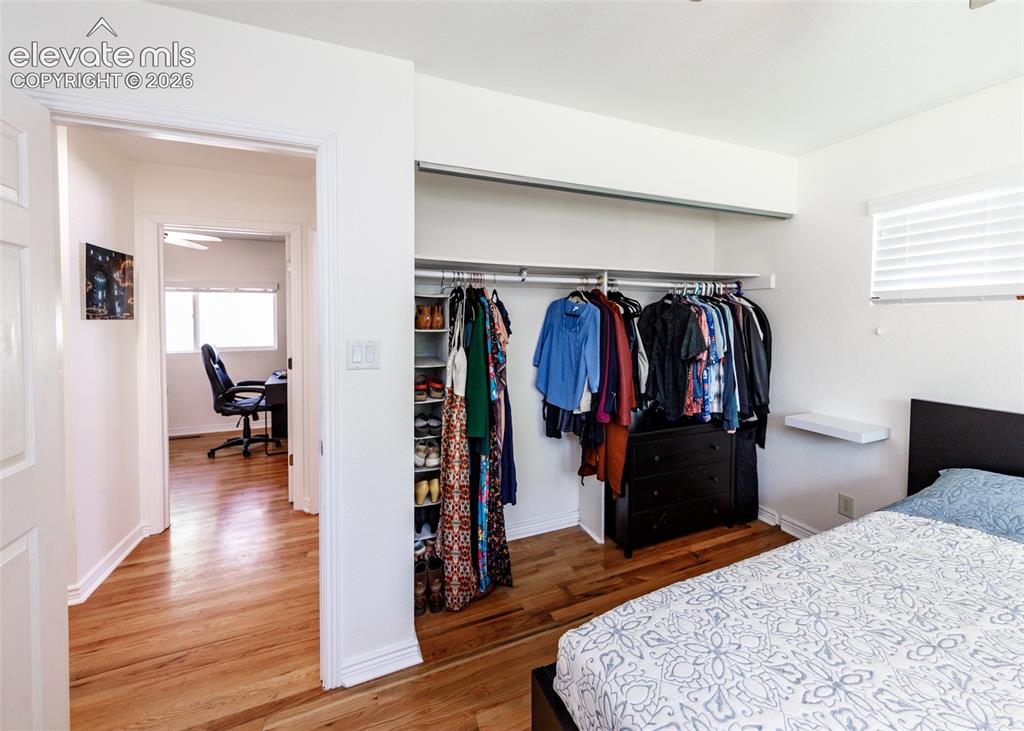 Image 20 of 47: Hardwood flooring, open closet with built-in shelving, window with blinds, 