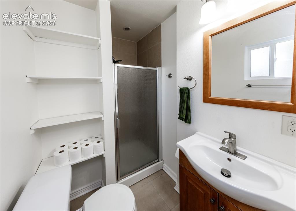 Image 21 of 47: White vanity with a single basin sink, brushed nickel faucet, and a wood-fr