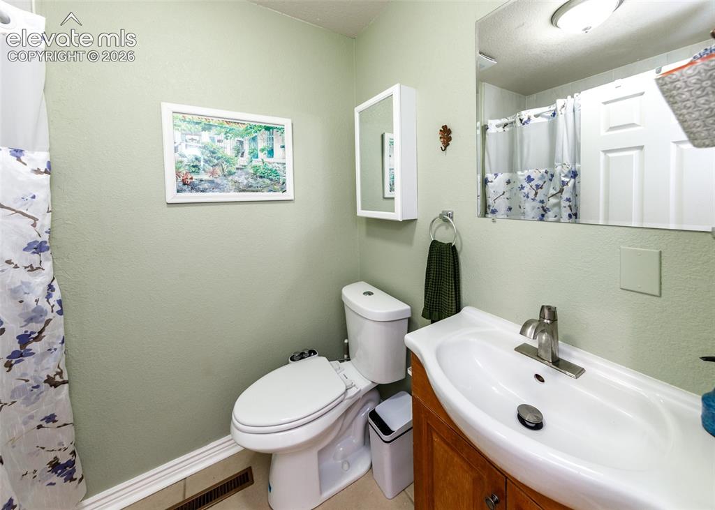 Image 25 of 47: Bathroom featuring a built-in wood-finish vanity, integrated sink, and wall