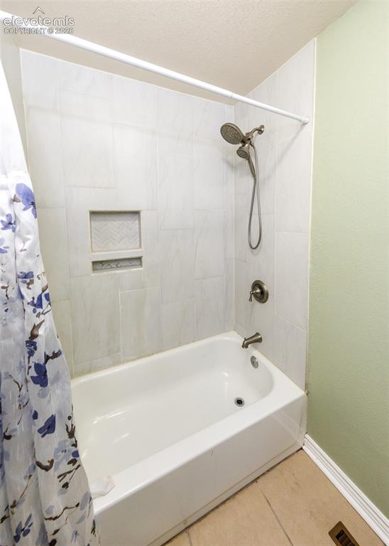 Image 26 of 47: Bathtub with wall-mounted shower fixture, tiled surround with recessed nich
