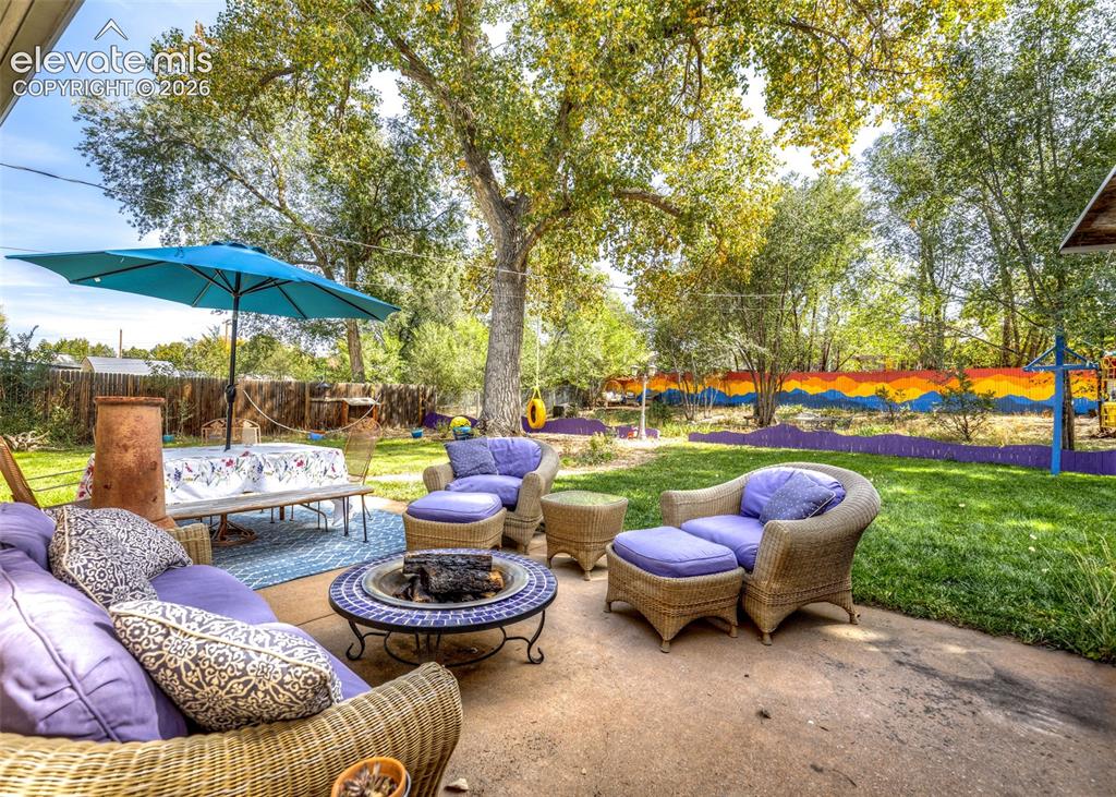Image 27 of 47: Expansive outdoor patio with concrete surfacing, a built-in fire pit, and m