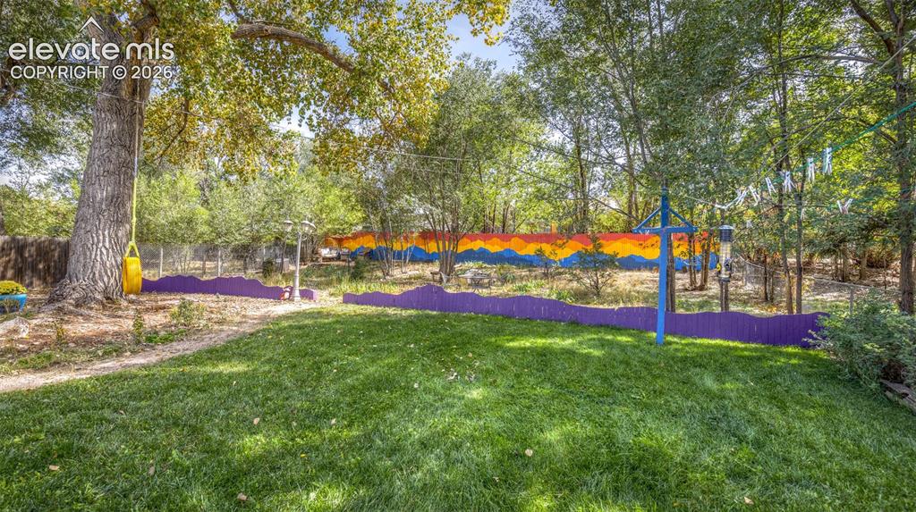 Image 29 of 47: Manicured lawn with mature trees and vibrant fencing