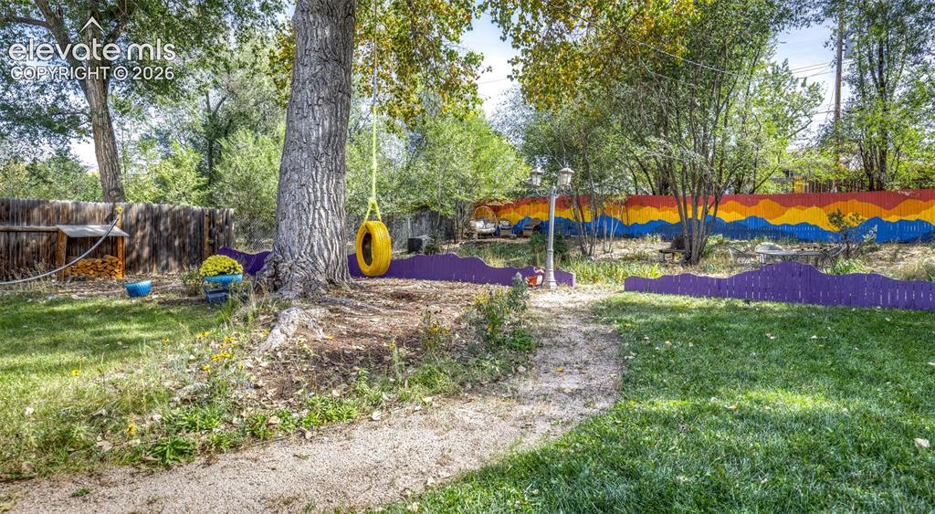 Image 30 of 47: Expansive yard featuring mature trees, a gravel pathway, and a painted priv