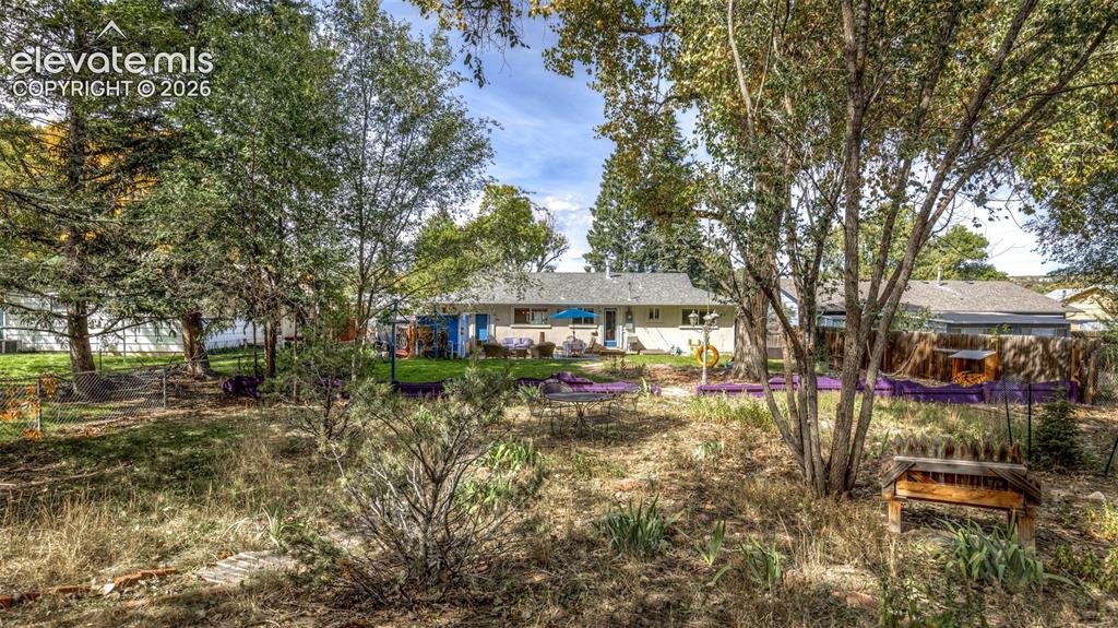 Image 39 of 47: Expansive backyard with a manicured lawn, mature trees, and an exterior pat