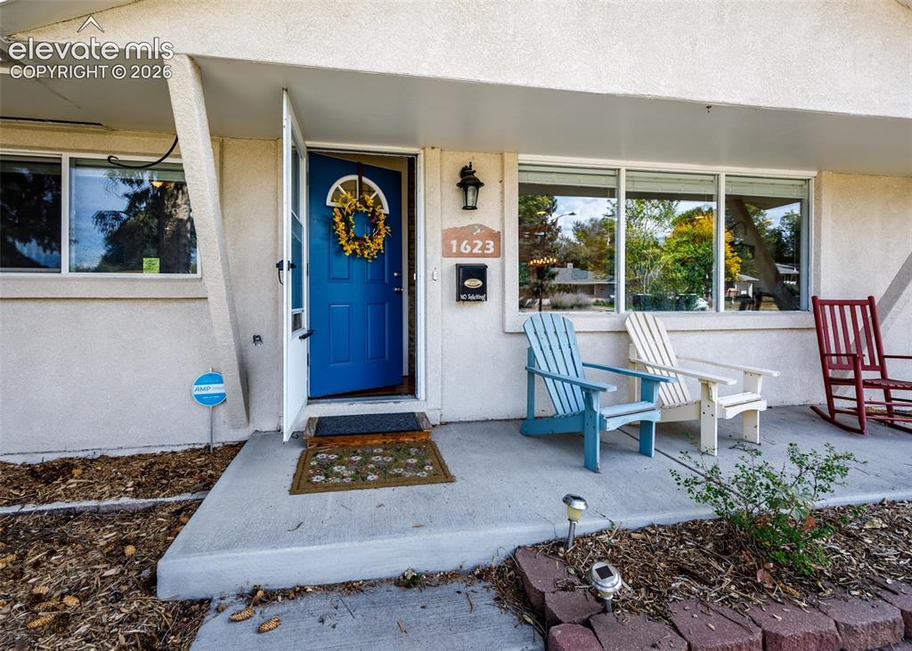 Image 4 of 47: Front entry featuring a vibrant blue door, white exterior, concrete porch, 