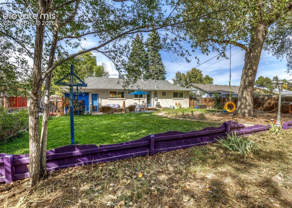 Image 40 of 47: Expansive backyard featuring a lush lawn, mature trees, and an exterior pat