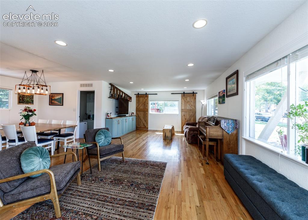 Image 5 of 47: Hardwood flooring, recessed lighting, white walls, and a multi-light chande