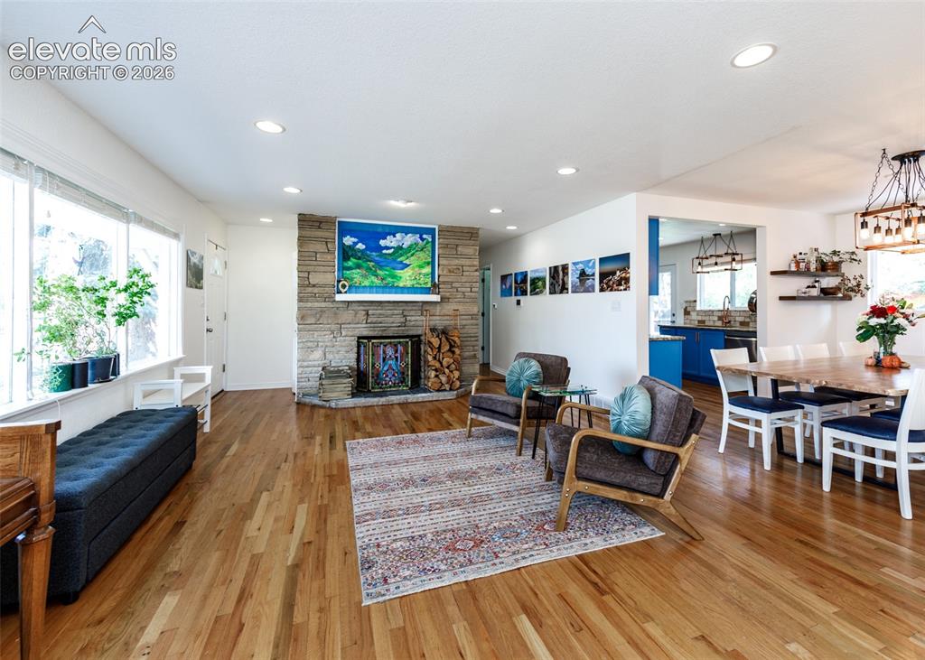 Image 6 of 47: Hardwood flooring, stone-clad fireplace, recessed lighting, expansive windo