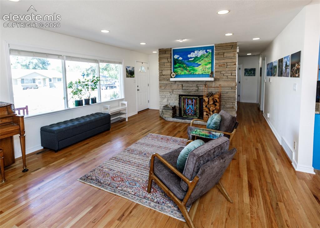 Image 8 of 47: Hardwood flooring throughout, stone fireplace with hearth, recessed lightin