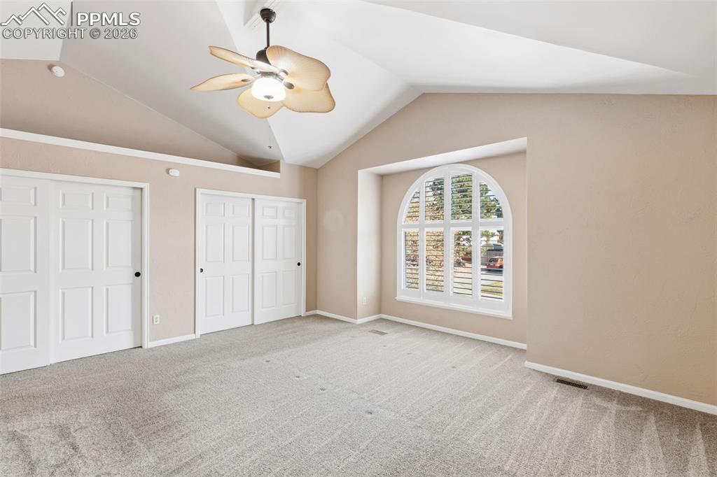 Image 28 of 49: The primary bedroom has a wall of closet and a large arched window to provi