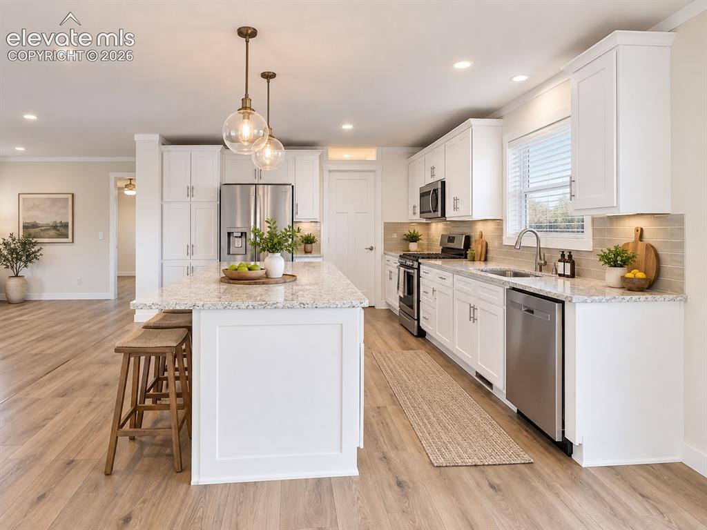 Image 12 of 47: Bright, open kitchen featuring white shaker-style cabinetry, expansive coun