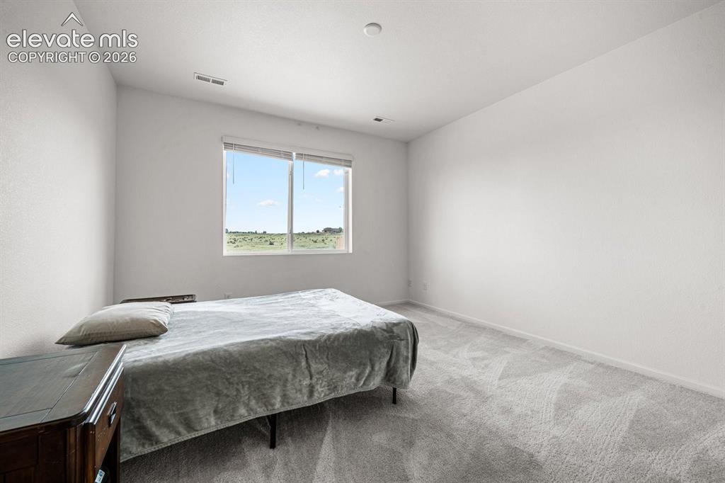 Image 12 of 25: Neutral wall finishes, recessed lighting, and a large window with roller sh
