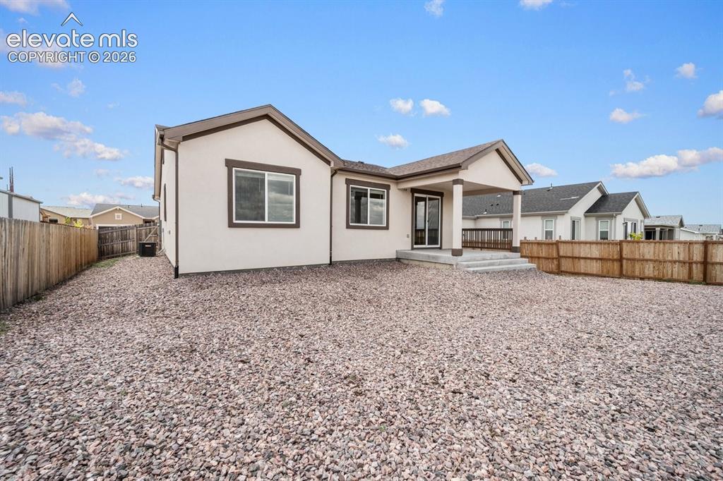 Image 20 of 25: Single-story stucco exterior with a covered patio, fenced yard, and a grave